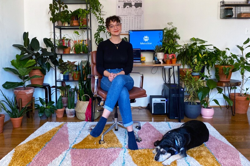 RD-open-source woman showing MetroStar Culture in front of working from home laptop station with her dog surrounded by plants