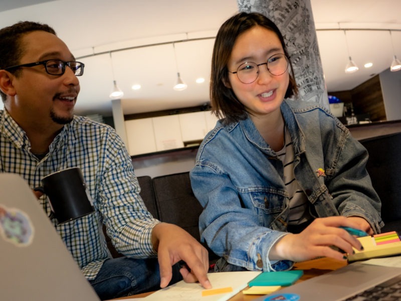 derek and eunice sitting around a coffee table in the MetroStar HQ break room collaborating on a project