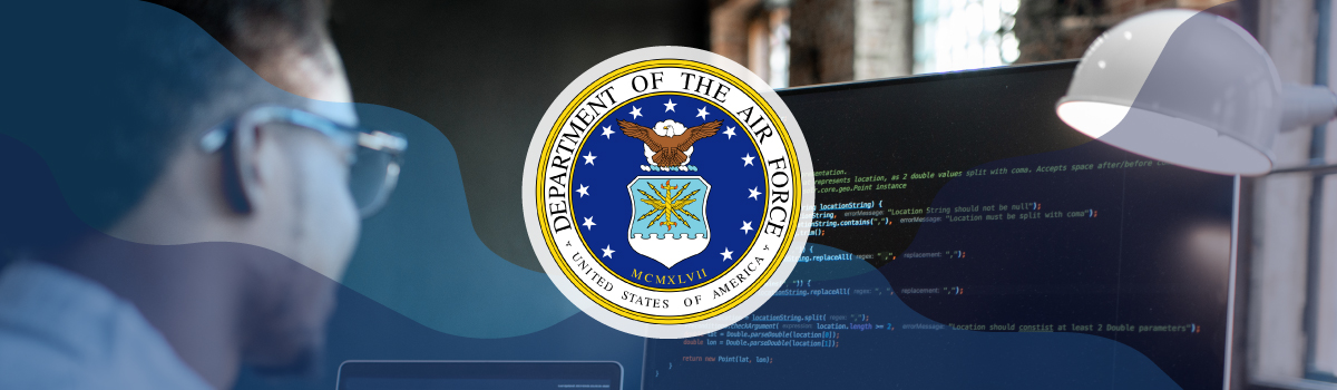 A man working at a desktop computer with coding displayed and the U.S. Air Force seal overlaid on the image