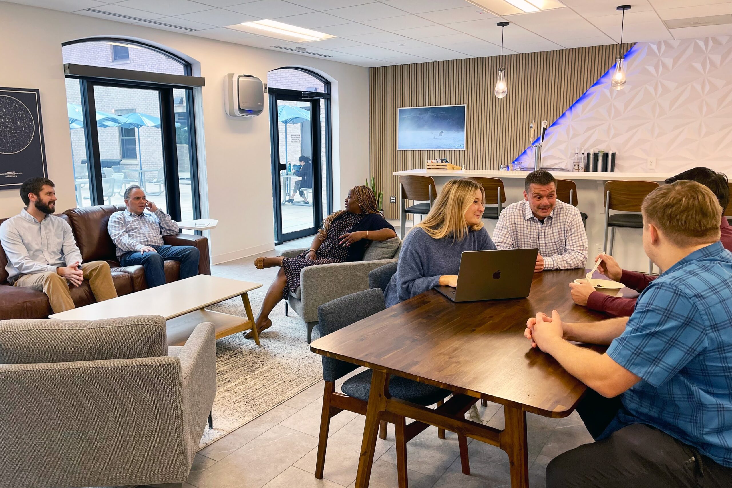 A group photo of MetroStar employees working in at various tables in the open-area