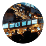 RAPTOR A dark image of a control room with personnel working at various stations with technical equipment, dashboards, and monitors